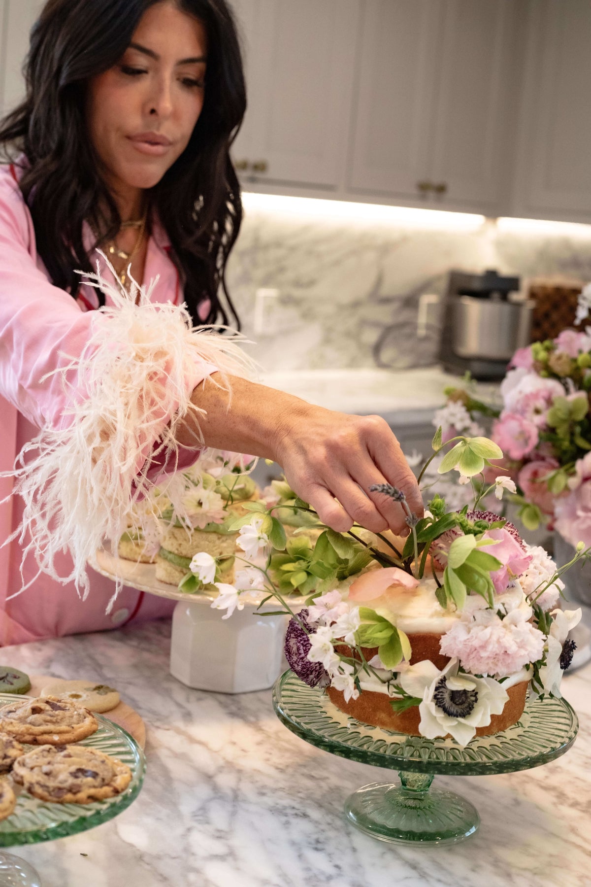 Woman arranging flowers on a cake in a kitchen setting